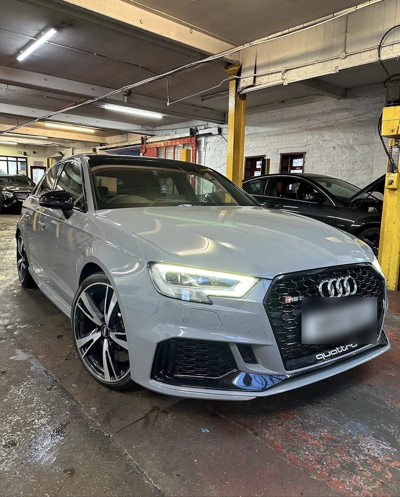 Grey Audi RS3 in the Surefix workshop with its lights on, after work was finished